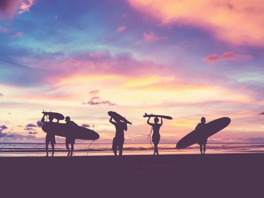 Surfers on the beach at sunset